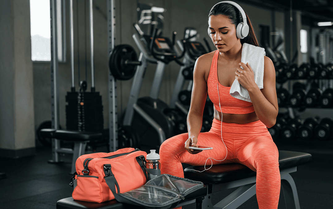 woman on work out bench in sports bra and leggings listening to music